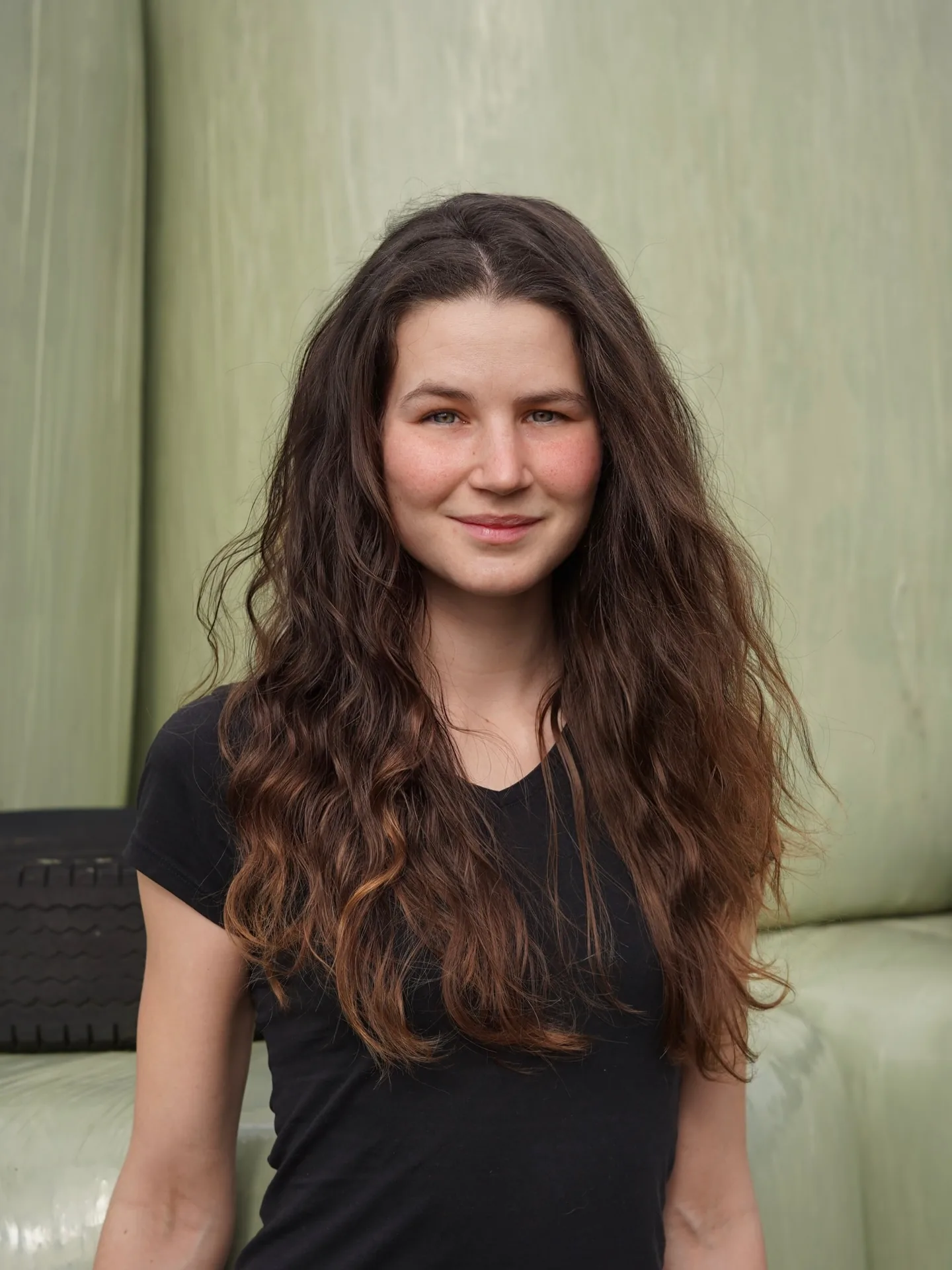 Frauenportrait mit langen Haaren auf grünem Sofa in warmem Licht