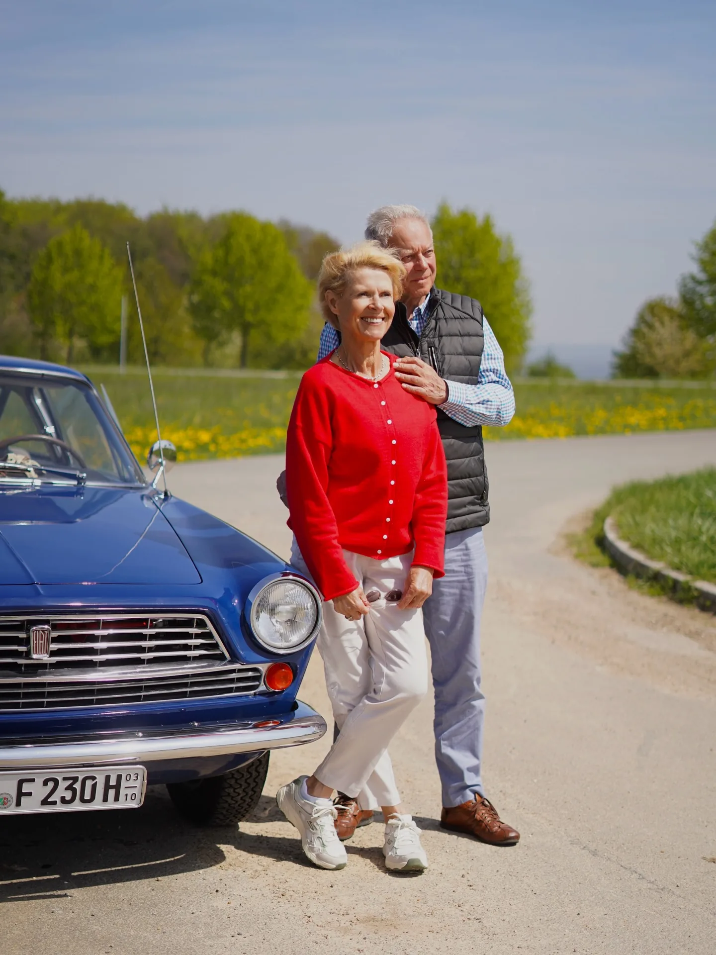 Seniorenpaar neben einem blauen Oldtimer